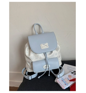 Détail du rabat bleu clair avec broderie de chat et imprimés de nœuds sur le sac à dos