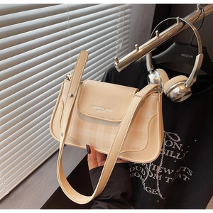 Détail du sac bandoulière crème avec motif à carreaux et bandoulière en cuir élégante