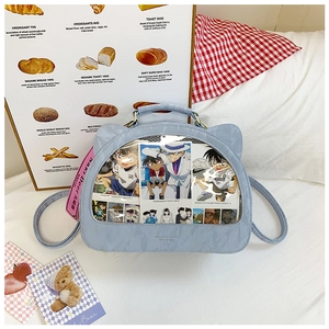 Detail view of cat-ear itabag with clear PVC window and blue glossy faux leather finish