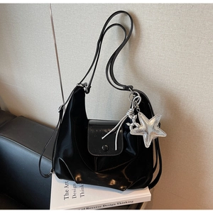 Détail d'un sac hobo noir brillant avec breloques étoile et chien ballon en argent