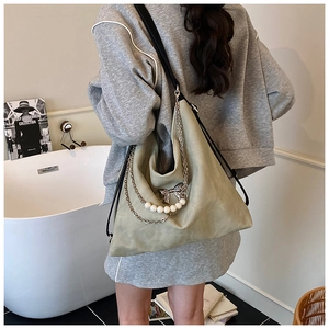 Detail of sage green hobo bag featuring silver chain, pearls and bow pendant
