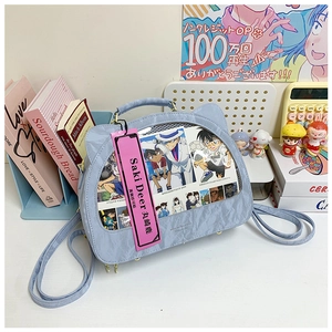 Macro shot of light blue cat-ear ITA bag showing transparent window and textured fabric