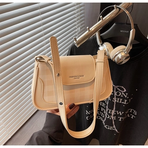 Détail du sac baguette en cuir crème avec lettrage doré et bandoulière réglable