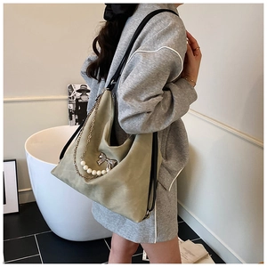 Detail of light green shoulder bag with silver bow hardware and pearl chain strap