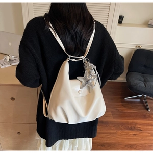 Détail d'un sac à dos hobo en cuir synthétique beige avec un pendentif étoile argenté