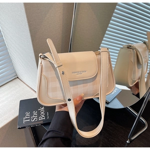 Gros plan du sac bandoulière crème avec texture cuir et détails métalliques argentés