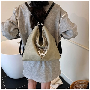 Detail of sage green triangular bag featuring silver metal chain, pearl accents, and bow