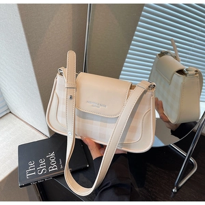 Détail du sac bandoulière en cuir crème avec une texture de tissu à carreaux subtile