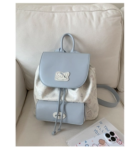 Détail du rabat en similicuir bleu clair et motifs d'ours sur un sac à dos en tissu doux