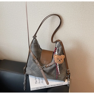 Detail der taupefarbenen Shopper-Tasche mit braunem Lederdeckel, Metallketten und Teddy-Anhänger