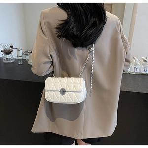 Close-up of white quilted leather crossbody bag with silver chain and twist lock on model