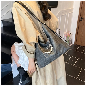 Detail of grey distressed leather tote with silver metal chains and pearl decorations