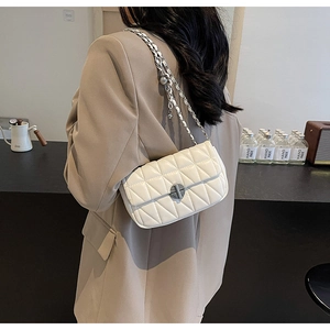 Detail of white quilted crossbody bag with silver chain strap and metal swivel lock