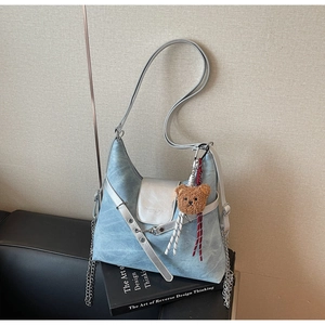 Detail der hellblauen Denim-Tasche mit silberner Klappe und süßem braunem Teddybär-Anhänger