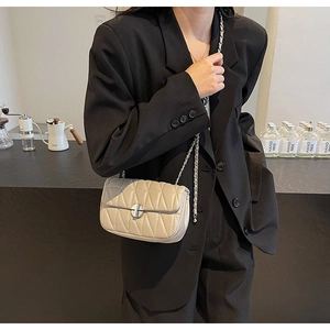 Chic beige quilted shoulder bag with silver chain strap worn by model in black blazer