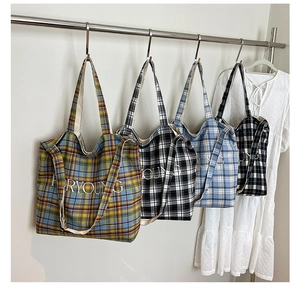 Detail view of four colorful plaid canvas tote bags with FORYOUNG embroidery on a hanger