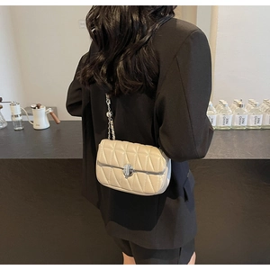 Detail of beige quilted shoulder bag with geometric stitching and silver metal lock