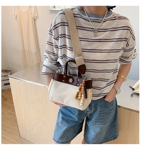 Detalle de bolso tote de lona con ribete de cuero y amuleto de cuentas bohemio