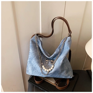Detail of light blue denim shoulder bag with white pearls and silver bow charm