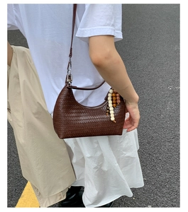 Close-up of dark brown woven leather hobo bag with bohemian wooden bead charm and silver zipper