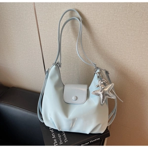 Détail d'un sac hobo en cuir verni bleu avec breloque étoile de mer et rabat frontal