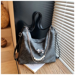 Detail of dark grey textured shoulder bag with pearl chain and silver bow decoration