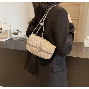 Beige quilted leather crossbody bag with chain strap shown on a model in a cafe
