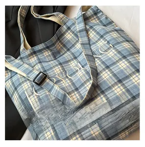 Detail shot of blue checkered canvas tote bag with white letter embroidery and adjustable strap