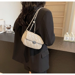 Detailed view of beige quilted bag with silver chain strap and metal lock closure