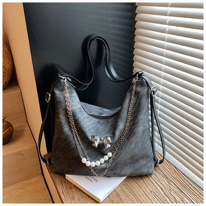 Detail of grey textured tote bag with silver bow pendant and elegant pearl chain