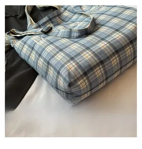 Detail of blue plaid canvas bag featuring woven texture and adjustable buckle strap