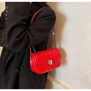 Detail of red quilted leather handbag with silver chain strap on a black blazer
