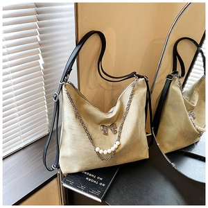 Detail of hobo bag featuring white pearls, metal chain, and bow knot ornament
