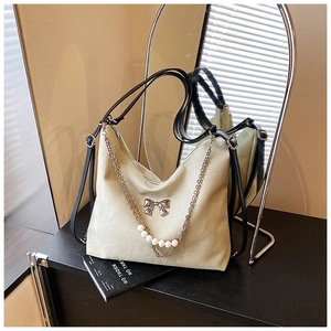 Detail of beige hobo shoulder bag with silver bow buckle and white pearl chain decoration