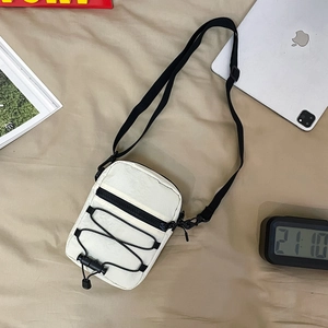 Detail of white nylon crossbody bag featuring black zipper pocket and bungee cord texture