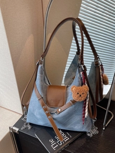Minimalistische hellblaue Tragetasche mit braunen Lederriemen und Plüschbär-Anhänger