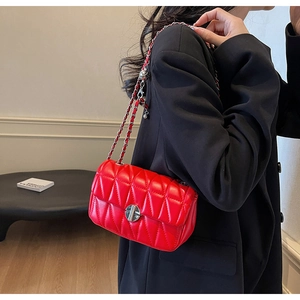 Detail of red quilted small square bag featuring silver chain strap and twist lock