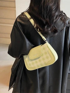 Petit sac bandoulière à carreaux vert clair avec rabat en cuir sur veste noire
