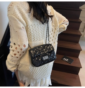Détail du sac à main matelassé noir avec chaîne argentée et fermoir pivotant chic