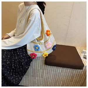 Détail d'un sac à bandoulière en crochet blanc avec des motifs floraux 3D colorés
