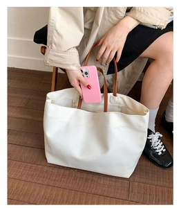 Detail of large white canvas tote bag interior being used to store a smartphone