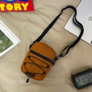 Detailed view of yellow nylon crossbody bag with zipper and adjustable strap on a flat lay