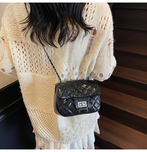 Détail du sac matelassé noir avec fermoir rotatif argenté sur cuir verni brillant