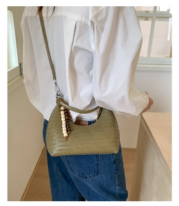 Olive green woven hobo bag with beaded zipper detail shown on a model's shoulder