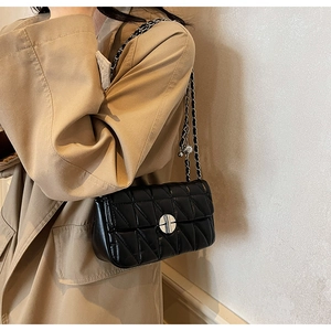 Detailed close-up of a black quilted shoulder bag featuring a silver round metal lock
