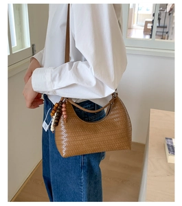 Detail of a brown woven leather hobo bag featuring decorative wooden bead accents