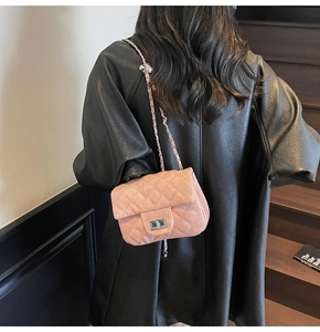 Détail d'un sac bandoulière rose matelassé avec chaîne et fermoir pivotant sur l'épaule