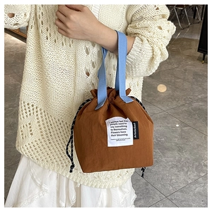 Detail of drawstring lunch bag in brown nylon with contrast blue handles and text tag