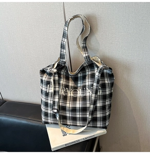 Detail of black and white checkered canvas tote bag with FOR YOUNG print on a bench