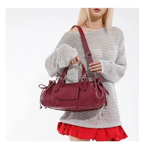 Detail of burgundy leather travel bag with adjustable strap and side drawstring accent